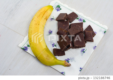 Banana and dark chocolate pieces on a napkin. 132186746