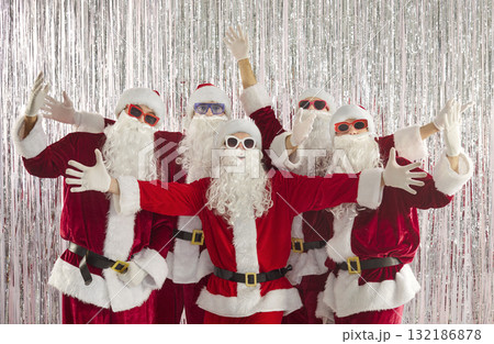 Santa team posing with open arms at corporate holiday party, silver backdrop 132186878