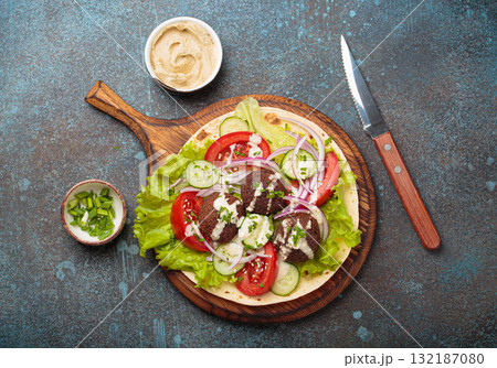 Preparing and cooking falafel wrap on pita on wooden cutting board with hummus top view Preparing and cooking falafel wrap on pita on wooden cutting board with hummus top view 132187080