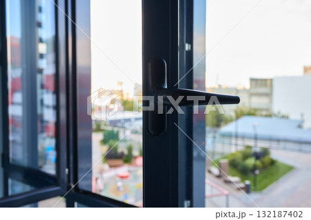 A contemporary window equipped with an open handle that offers a beautiful view of the cityscape A contemporary window equipped with an open handle that offers a beautiful view of the cityscape 132187402
