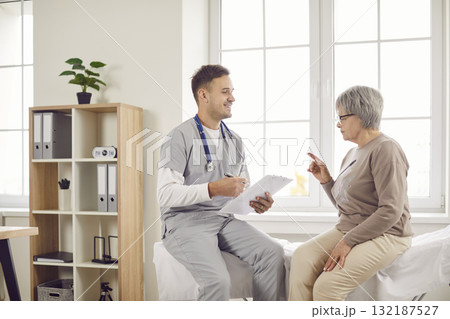Young happy doctor, male nurse and old woman talking, explaining, taking social healthcare 132187527