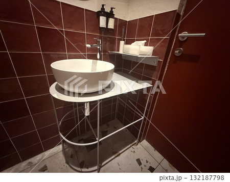 Bathroom sink with metal shelves, red tiles, and white accessories in warm lighting. Order, hygiene, and minimalism representing modern interior design aesthetics. Bathroom sink with metal shelves, red tiles, and white accessories in warm lighting. Order, hygiene, and minimalism representing modern interior design aesthetics. 132187798
