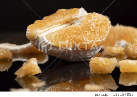an orange citrus on a black mirror surface, ripe sweet and juicy citrus is reflected on the black surface 132187853