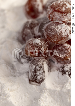 dried kumquat and powdered white sugar, sweet dried orange kumquat fruits in white powdered sugar, closeup dried kumquat and powdered white sugar, sweet dried orange kumquat fruits in white powdered sugar, closeup 132187857