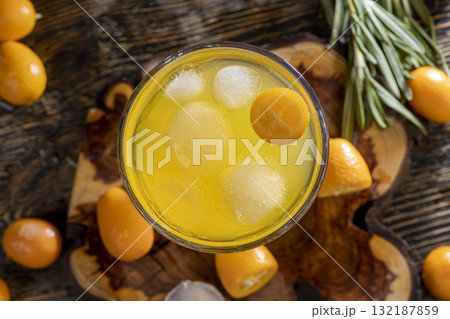 citrus-flavored orange juice and fresh kumquat fruits , delicious and fresh orange juice and fresh kumquat fruits next to a glass 132187859