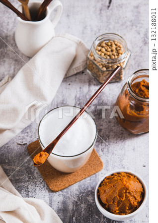 Miso-Spiked latte in a glass and a bowl of miso paste on the table vertical view Miso-Spiked latte in a glass and a bowl of miso paste on the table vertical view 132188011