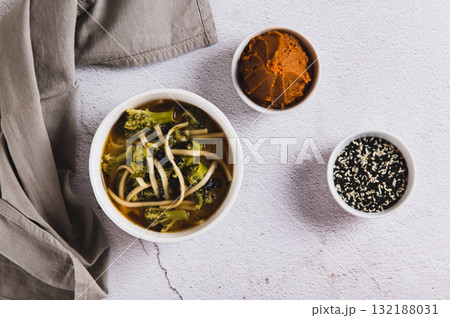 Delicious miso soup with noodles and broccoli in a bowl on the table top view Delicious miso soup with noodles and broccoli in a bowl on the table top view 132188031