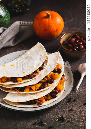 Spicy vegetable tacos with beans and pumpkin on a plate on the table vertical view Spicy vegetable tacos with beans and pumpkin on a plate on the table vertical view 132188039