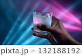 Celebratory drink enjoyed during vibrant party atmosphere with colorful lights 132188192