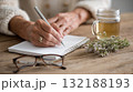Writing in a notebook with tea and flowers on a cozy wooden table 132188193