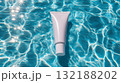 Sunscreen tube mockup floats on shimmering pool water under bright sunlight 132188202