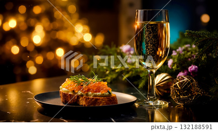 A glass of champagne and a plate of food on a table 132188591