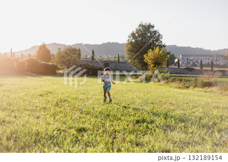 panoramic view of one small happy girl running on the field in the evening during sunset panoramic view of one small happy girl running on the field in the evening during sunset 132189154