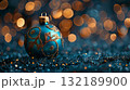 A blue and gold ball sits on a pile of gold and brown twigs. Christmas blue background 132189900
