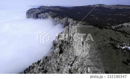 Aerial view flying over rocky mountain cliffs above clouds. Media Aerial view flying over rocky mountain cliffs above clouds. Media 132190347