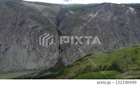 Waterfall cascading down rocky mountainside in serene valley. Media Waterfall cascading down rocky mountainside in serene valley. Media 132190490