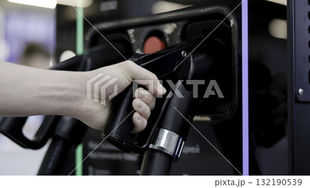Hand grabbing electric vehicle charger at station. Media Hand grabbing electric vehicle charger at station. Media 132190539