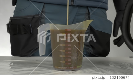 Worker pouring brown liquid chemical into measuring cup. Creative Worker pouring brown liquid chemical into measuring cup. Creative 132190674