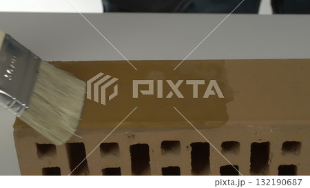 Applying water repellent primer on a perforated clay brick. Creative 132190687