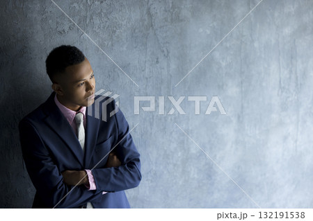 壁際に立っているスーツを着た男性　 132191538