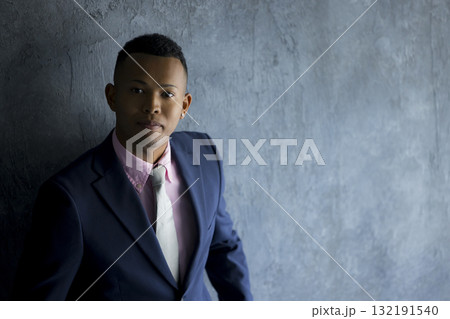壁際に立っているスーツを着た男性　 132191540