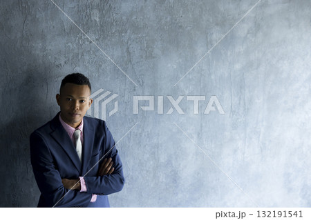 壁際に立っているスーツを着た男性　 132191541