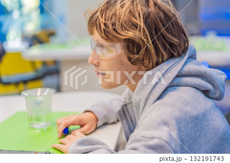 Teenage boy wearing safety glasses prepares to conduct chemistry experiments, representing STEM education, curiosity, and the excitement of hands-on scientific discovery 132191743
