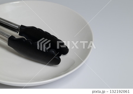 白い皿と黒いトング シンプルな調理器具 132192061
