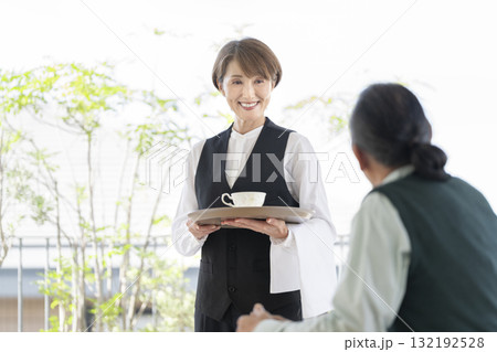 カフェの女性スタッフとシニア男性 カフェの女性スタッフとシニア男性 132192528