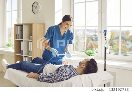 Happy, smiling female nurse taking care of male patient who is receiving vitamin therapy Happy, smiling female nurse taking care of male patient who is receiving vitamin therapy 132192788