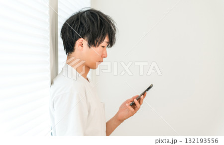 スマホを見ながら落ち込む若いアジア人男性 スマホを見ながら落ち込む若いアジア人男性 132193556