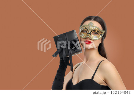 Woman in elegant attire holds a gift wrapped with a bow Woman in elegant attire holds a gift wrapped with a bow 132194042