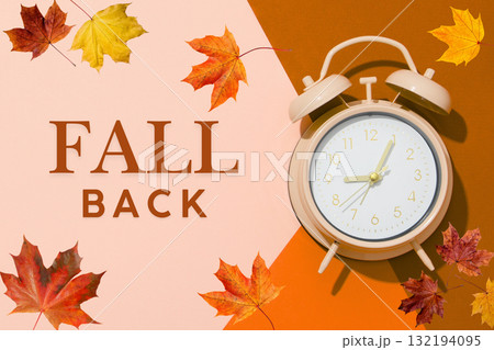 Clock on a brown and pink background with autumn leaves Clock on a brown and pink background with autumn leaves 132194095