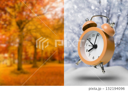 A clock stands tall before autumn trees and snow A clock stands tall before autumn trees and snow 132194096