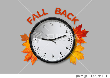 Clock surrounded by decorative autumn leaves on gray background Clock surrounded by decorative autumn leaves on gray background 132194101