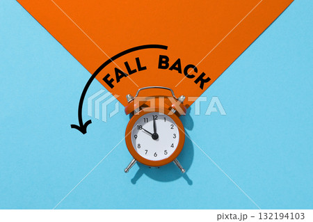 Vintage orange alarm clock placed against a blue background Vintage orange alarm clock placed against a blue background 132194103