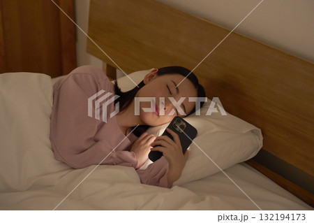布団の中でスマホを使いながら寝落ちする女性 布団の中でスマホを使いながら寝落ちする女性 132194173