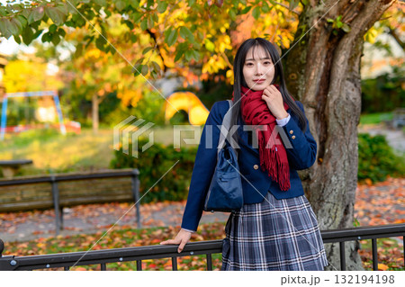 紅葉を背に休憩する女子高生 冬服で通学する高校生 登校下校 紅葉を背に休憩する女子高生 冬服で通学する高校生 登校下校 132194198
