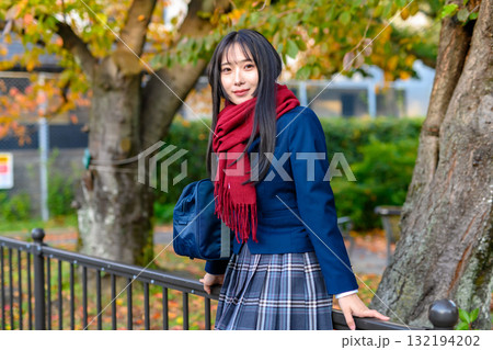 紅葉を背に休憩する女子高生　冬服で通学する高校生　登校下校　 132194202