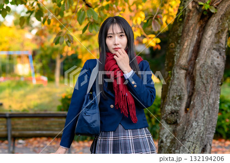 紅葉を背に休憩する女子高生　冬服で通学する高校生　登校下校　トリミングアップ 132194206