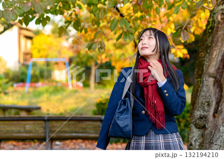 紅葉を背に休憩する女子高生　冬服で通学する高校生　登校下校　トリミングアップ 132194210
