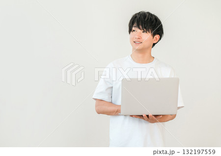 パソコンを持つTシャツ姿の若いアジア人男性（投資,個人投資家,資産運用） 132197559