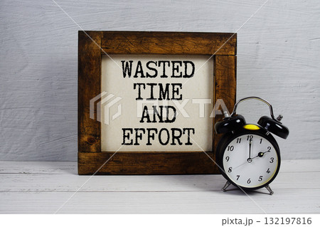 Wasted Time And Effort text with alarm clock on wooden background Wasted Time And Effort text with alarm clock on wooden background 132197816