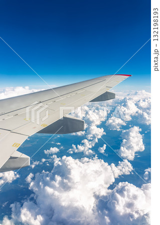 View from the airplane window at a beautiful cloudy sky and the airplane wing 132198193