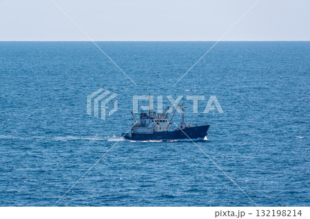 Fishing boat in blue sea and clear sky with birds flying overhead. 132198214