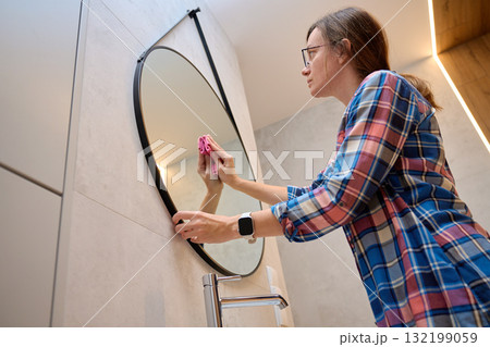 Woman cleaning bathroom mirror with cloth Woman cleaning bathroom mirror with cloth 132199059