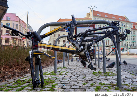 Damaged bicycle frame locked to bike rack on city street 132199078