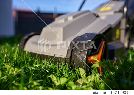 Electric lawnmower on green grass in backyard 132199090