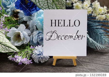 Hello December text write on paper card with wooden easel and flowers decoration on wooden background 132199169