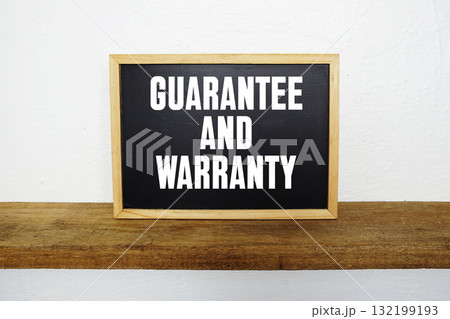 Blackboard with text "Guarantee And Warranty" on a wooden shelf, set against a white wall. Blackboard with text "Guarantee And Warranty" on a wooden shelf, set against a white wall. 132199193